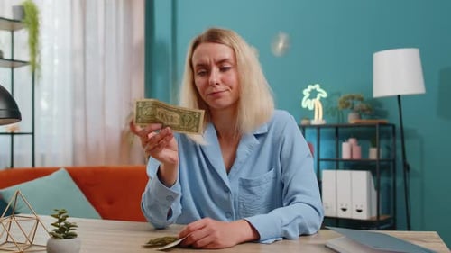Woman Counting Dollar Bills at Desk, Looks Worried