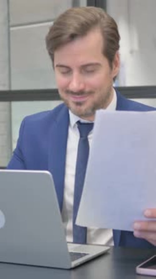 Happy Man in Suit Receives Good News at Desk
