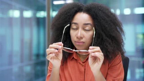 Young Adult Woman Removes Glasses, Rubs Tired Eyes