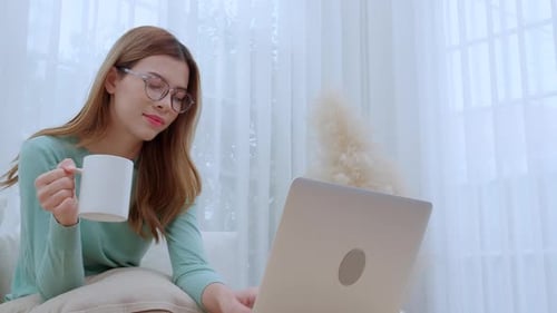 Woman Works on Laptop with Coffee at Home
