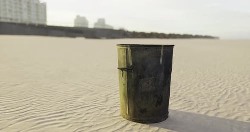 Lonely Trash Can Rests on the Sandy Beach at Sunrise in a Quiet Coastal Town