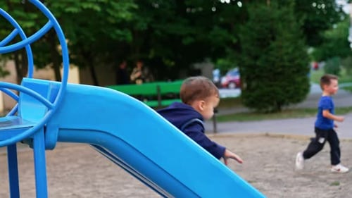 Toddler Plays near Slide at Park Playground