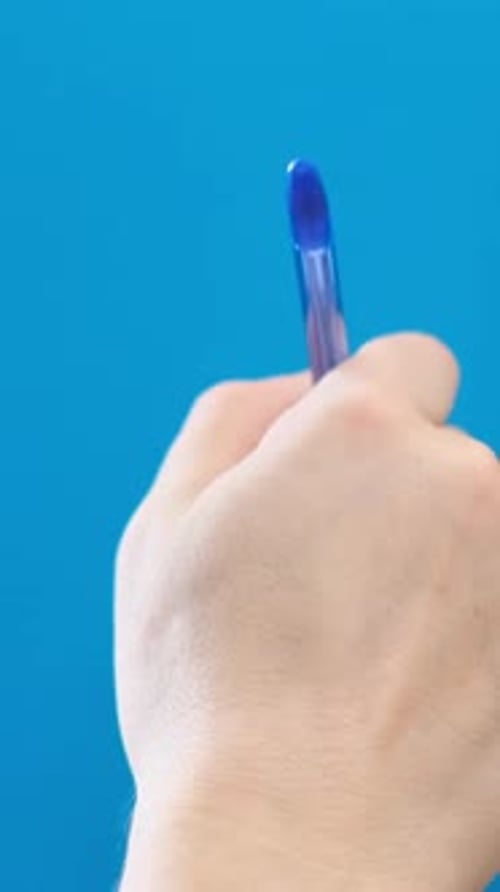Close Up of Male Hand Writing Text with Ballpoint Pen on Blue Chromakey Background Vertical Video