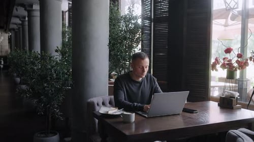 Travailleur indépendant travaillant à distance à l'aide d'un ordinateur portable et d'une connexion Wi-Fi gratuite dans un café de ville moderne, emploi en ligne à temps partiel