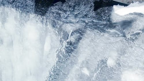 Icy waterfall flowing underneath a frozen glacier in winter nature background