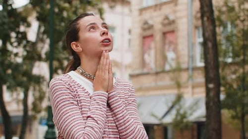 Woman Praying Outdoors in Urban Setting