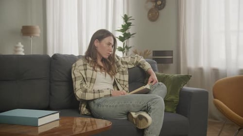 Young Woman Reading a Book on the Couch