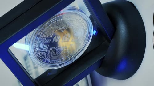 Einzelner Bitcoin im Rahmen, der sich langsam dreht und Licht reflektiert. Vertikales Video