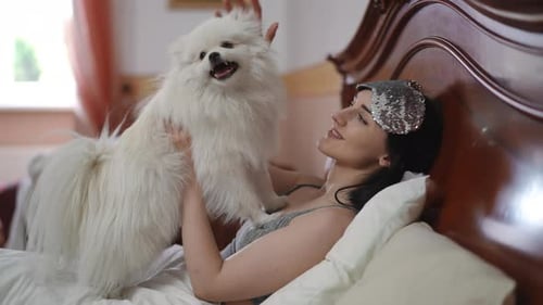 Woman Cuddles Pet Dog in Bed