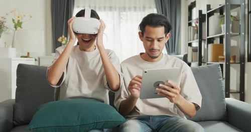 Young Couple Using VR Headset and Tablet at Home