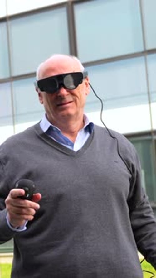 Aged Man Interacting with Augmented Vision Goggles Outside the Office