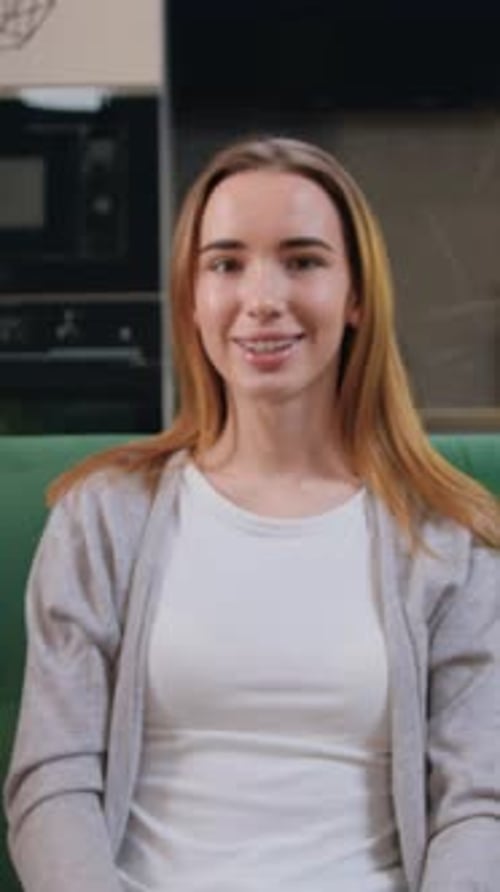 Smiling woman with braces sitting indoors on a couch