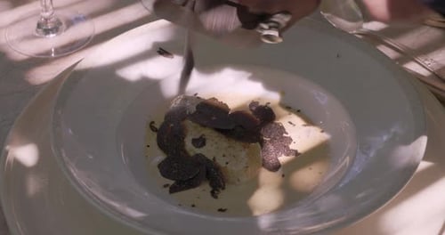 close-up shot of a dish in Provence, France, with sliced black truffles and a creamy sauce, being ga