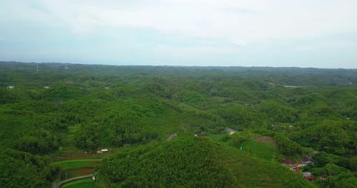 Luftbild kleiner Hügel, bewachsen mit dichten Waldbäumen und bewölktem Himmel. Gunung Kidul, Wonos