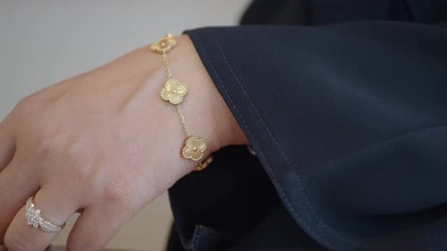 Elegant Gold Bracelet Showcased on a Hand with Dark Fabric