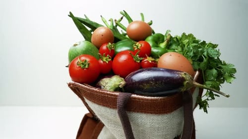 Verduras frescas en bolsa reutilizable, una variedad de verduras frescas que salen de una bolsa reutilizable, incluye