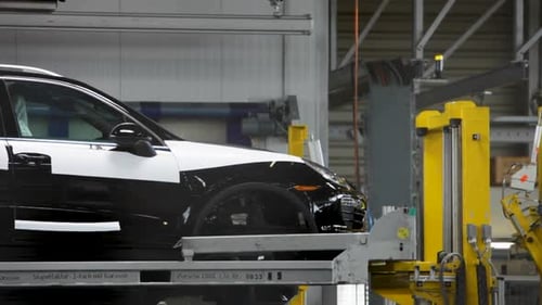 Voiture de luxe noire sur la chaîne de montage dans une usine industrielle, intérieur lumineux