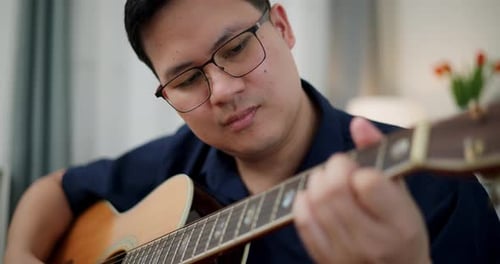 Adult Playing Acoustic Guitar in Home Interior