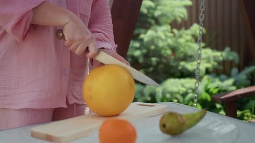 Femme tranchant le melon, femme décontractée, préparant des fruits frais pour un pique-nique en plein air, scène d'arrière-cour ensoleillée avec