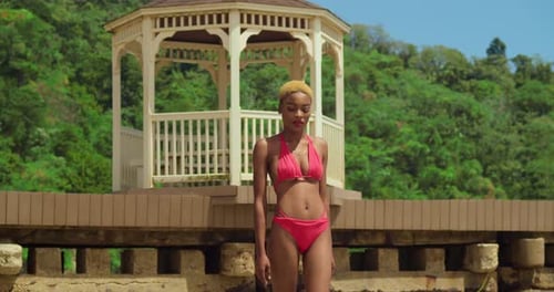 A girl with black skin embraces the beauty of a white sand beach in the Caribbean, adorned in a red