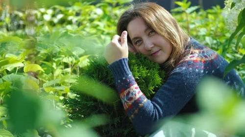 femme souriante étreignant des plantes dans un magasin de jardin