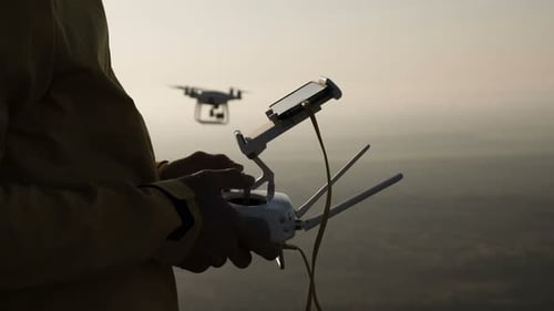 Man controls drone technology with smart phone on sunny mountain hike