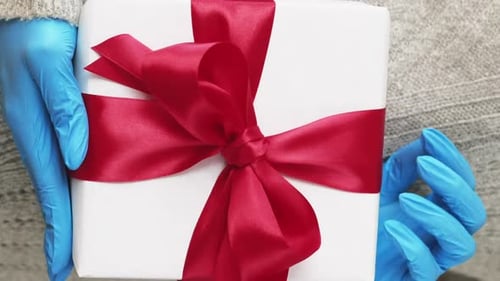 Hands in Gloves Hold White Christmas Gift