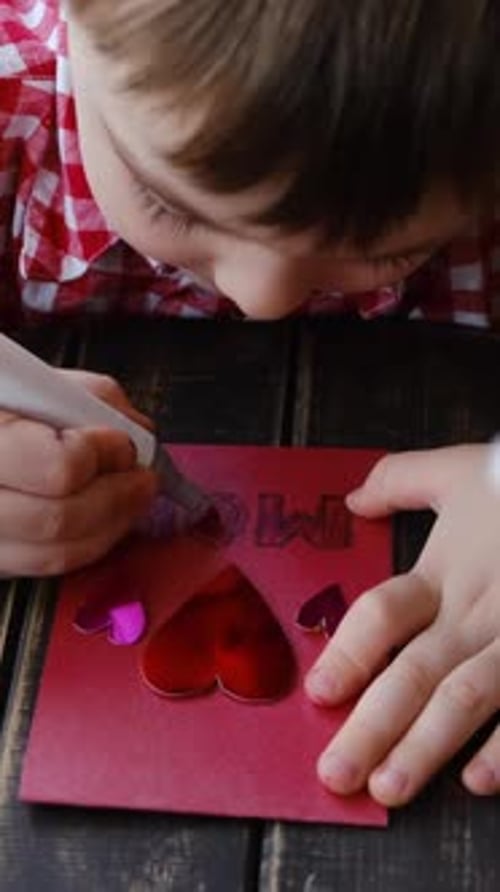 Young Child Making Card for Mom on Table