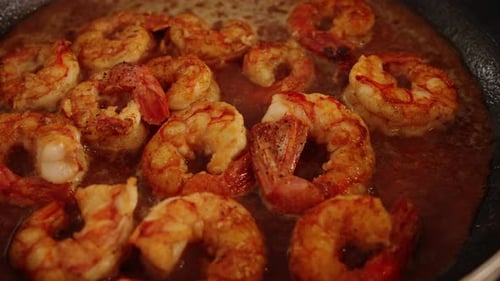 Extreme close up shot of delicious peeled shrimps, simmering and boiling on hot pan, reducing and ab