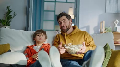 Father and Son Relaxing on Couch Watching Television