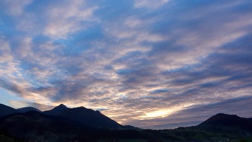 Farbenfrohe Wolken in der Abenddämmerung zur Goldenen Stunde Blauer Himmel und Silhouette eines Berges