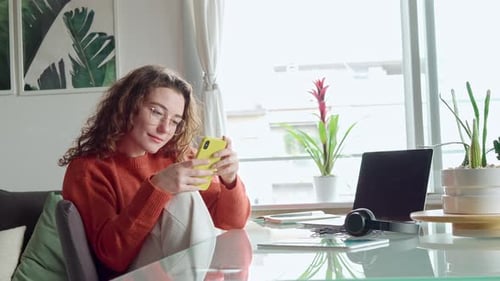 Smiling Young Woman Holding Cell Phone Using Smartphone at Home