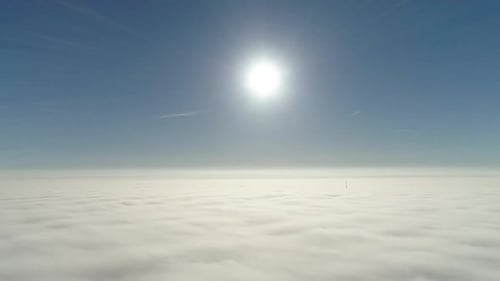 Flug über neblige Wolken im morgendlichen Sonnenlicht mit wenig Glanz und Stadtbild unter Wolken