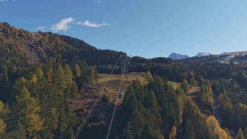 Scenic cable car with majestic peaks in view, sunny day, aerial.