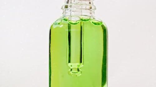 Dropping Clear Glass Vial Into Green Liquid