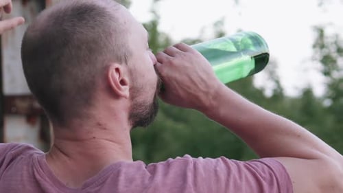 Un homme affligé boit de l'alcool dans un bâtiment abandonné. Le concept de dépendance à l'alcool.