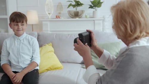 Senior woman taking picture of boy with camera