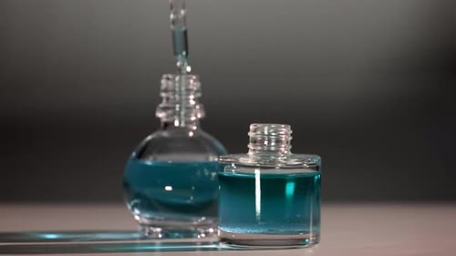 Produto de perfume, perfumaria e óleo essencial. Gotas caindo da pipeta cosmética para o frasco de vidro