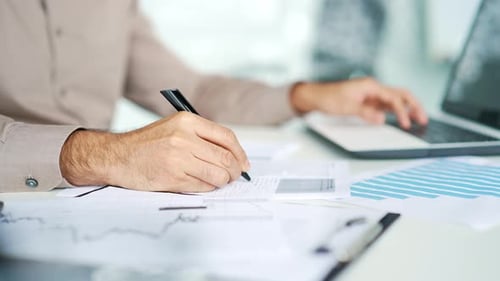 Close up. Man's hand fills out a form documents with a pen at a desk at a workplace in business