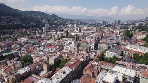 Aerial: Sarajevo cityscape, Sacred Heart Cathedral, rolling hills, urban buildings