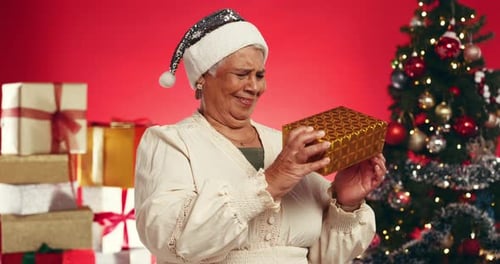 Christmas, gift and shake with old woman and smile in studio for announcement