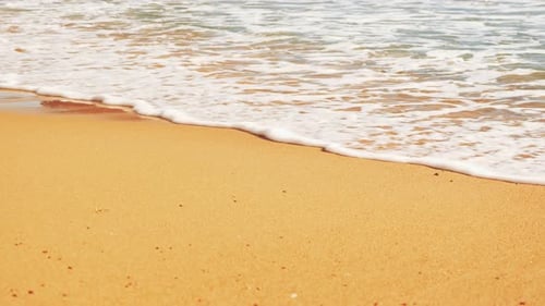 Sea waves reaching sandy beach, close up.