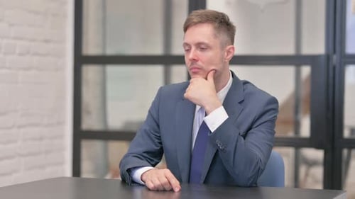 Man in Suit Thinking at Desk