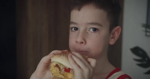 Child Eats Tasty Hamburger Inside House Close Up