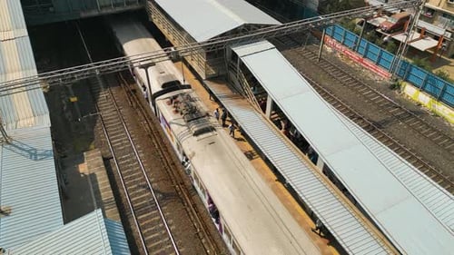 Luftaufnahme eines Nahverkehrszuges, der am belebten Bahnhof ankommt