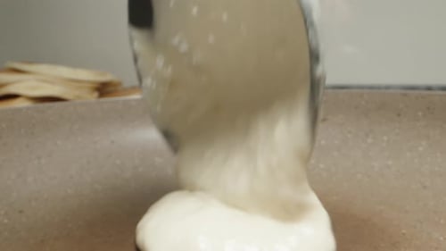 I pour the pancake batter into the pan. Dolly slider extreme close-up.