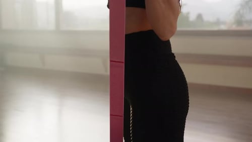 Woman Strengthens Biceps And Arms With Pink Elastic At Gym