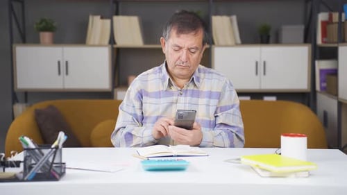 Adult Man Uses Phone at Desk