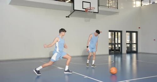 Basketball players stretching on court, preparing for practice session indoors