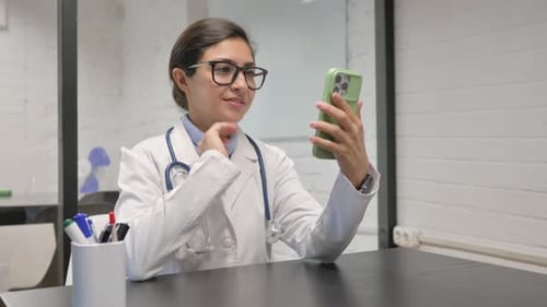 Online Video Chat by Indian Young Doctor on Phone in Clinic